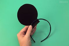 a hand holding a black paper mouse pad on top of a green surface with the mousepad attached to it