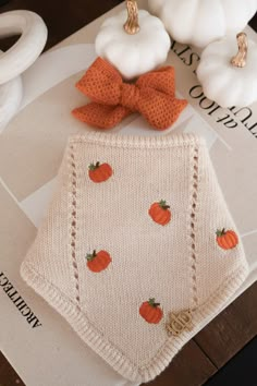 a knitted bib with pumpkins on it and a bow tie around the neck