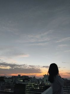 a woman standing on top of a roof looking at the sky