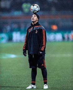 a man standing on top of a soccer field holding a soccer ball in his head