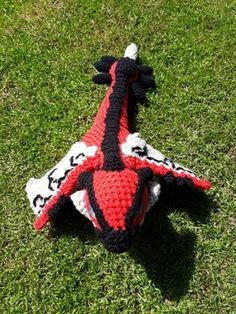 a crocheted toy lizard laying on the grass