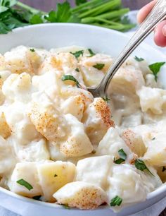 a white bowl filled with potato salad and garnished with parsley