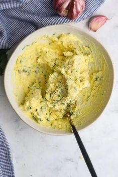 a bowl filled with mashed potatoes next to garlic