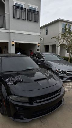 two black sports cars parked in front of a house