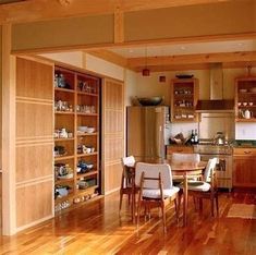 an open kitchen and dining room with wood flooring, built - in shelving