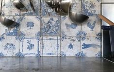 pots and pans are hanging on the wall in a kitchen with blue floral tiles