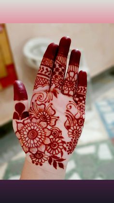 a woman's hand with henna on it and red nail polish applied to the palm