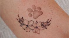 a dog's paw and flower tattoo on the back of a woman's shoulder