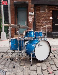 a blue drum set sitting on top of a brick road