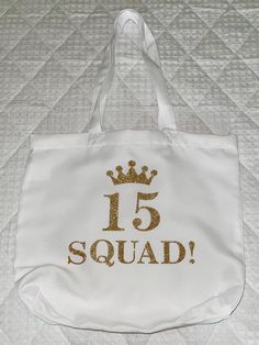 a white tote bag with the number 15 squad printed on it and a gold crown