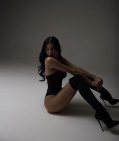 a woman is sitting on the floor with her legs crossed and wearing black high heels