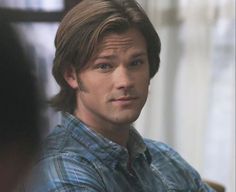 a close up of a person wearing a plaid shirt and looking at the camera with a serious look on his face