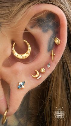 an ear with three different types of piercings on it's sides and one has a cross