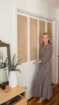 a woman standing in front of a door with her hand on the wall and smiling