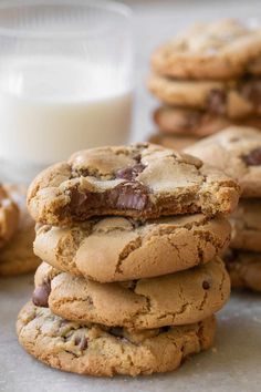 chocolate chip cookies stacked on top of each other with a glass of milk in the background