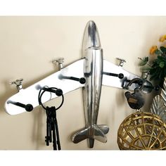 a metal airplane hanging on the wall next to a vase with flowers and other items