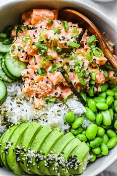 a bowl filled with rice, cucumbers and salmon on top of green beans