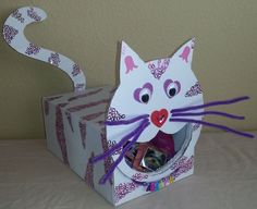 a paper cat with its mouth open and tongue out sitting in front of two boxes