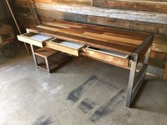 a table made out of wood and metal with two drawers on each side, sitting in front of a wooden wall