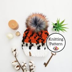 an orange and black knitted hat next to cotton flowers