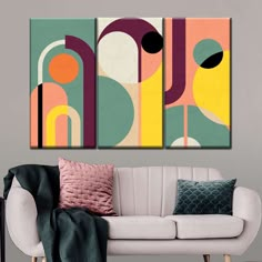 three abstract paintings hanging on the wall above a white couch in front of a gray wall