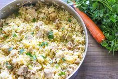 a pan filled with food next to carrots and parsley