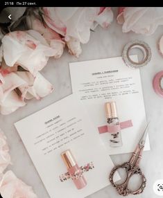 some pink flowers and scissors are on the table next to paper with writing in it