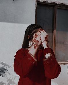 a woman in a red dress holding her hands up to her face and looking out the window