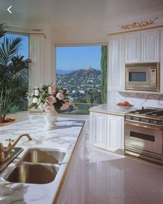 a large kitchen with marble counter tops and white cabinets, overlooking the hollywood hills outside