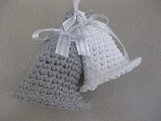 two gray and white crocheted hats hanging from a hook on a carpeted floor