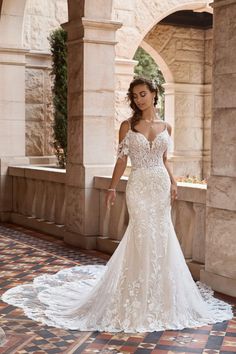 a woman in a white wedding dress standing on a tile floor with arches and archways