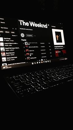 an open laptop computer sitting on top of a black table in the dark with its screen lit up