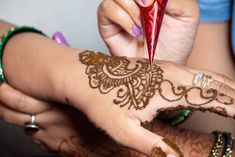 a woman with henna on her hand holding a red object in her other hand