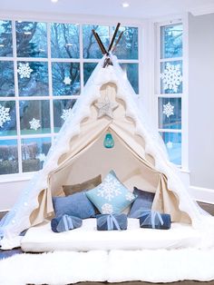 a teepee bed with snowflakes on the windowsill and pillows in front