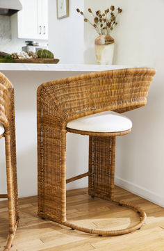 two wicker chairs sitting next to each other on a wooden floor in front of a counter