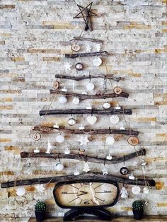 a christmas tree made out of branches and other items in front of a brick wall