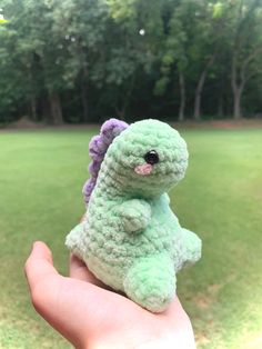 a small crocheted green and purple elephant sitting on top of a person's hand