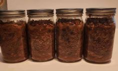 four jars filled with food sitting on top of a counter