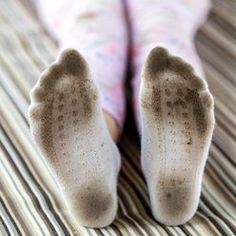 a person's feet are covered in dirt on a striped bed sheet with stripes