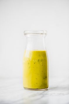 a glass jar filled with green liquid sitting on top of a white countertop next to a wall