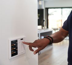 a man is pointing at an electronic device on the wall