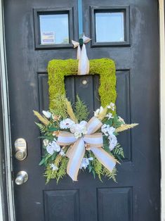 a wreath on the front door of a house decorated with flowers and grass is shown