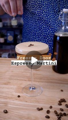 a person pouring coffee into a glass on top of a wooden table next to beans