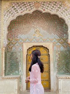 a woman standing in front of an ornate doorway