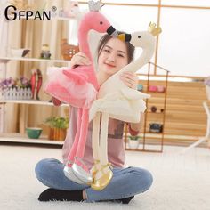 a woman sitting on the floor holding a stuffed flamingo