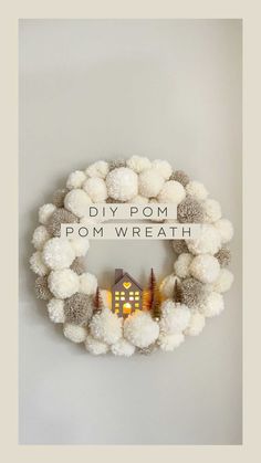 a white wreath with pom - poms hanging on the wall