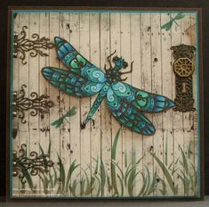 a blue dragonfly sitting on top of a wooden paneled wall next to green grass