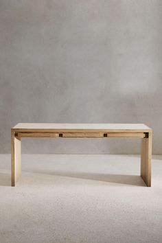 a wooden table sitting on top of a white floor next to a gray wall with no one around it