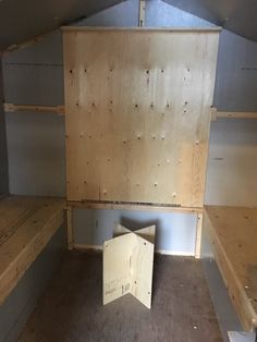 an empty room with wooden shelves and plywood boards on the wall, in which there is no one sitting or standing