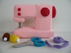 a pink sewing machine sitting on top of a table next to some scissors and yarn